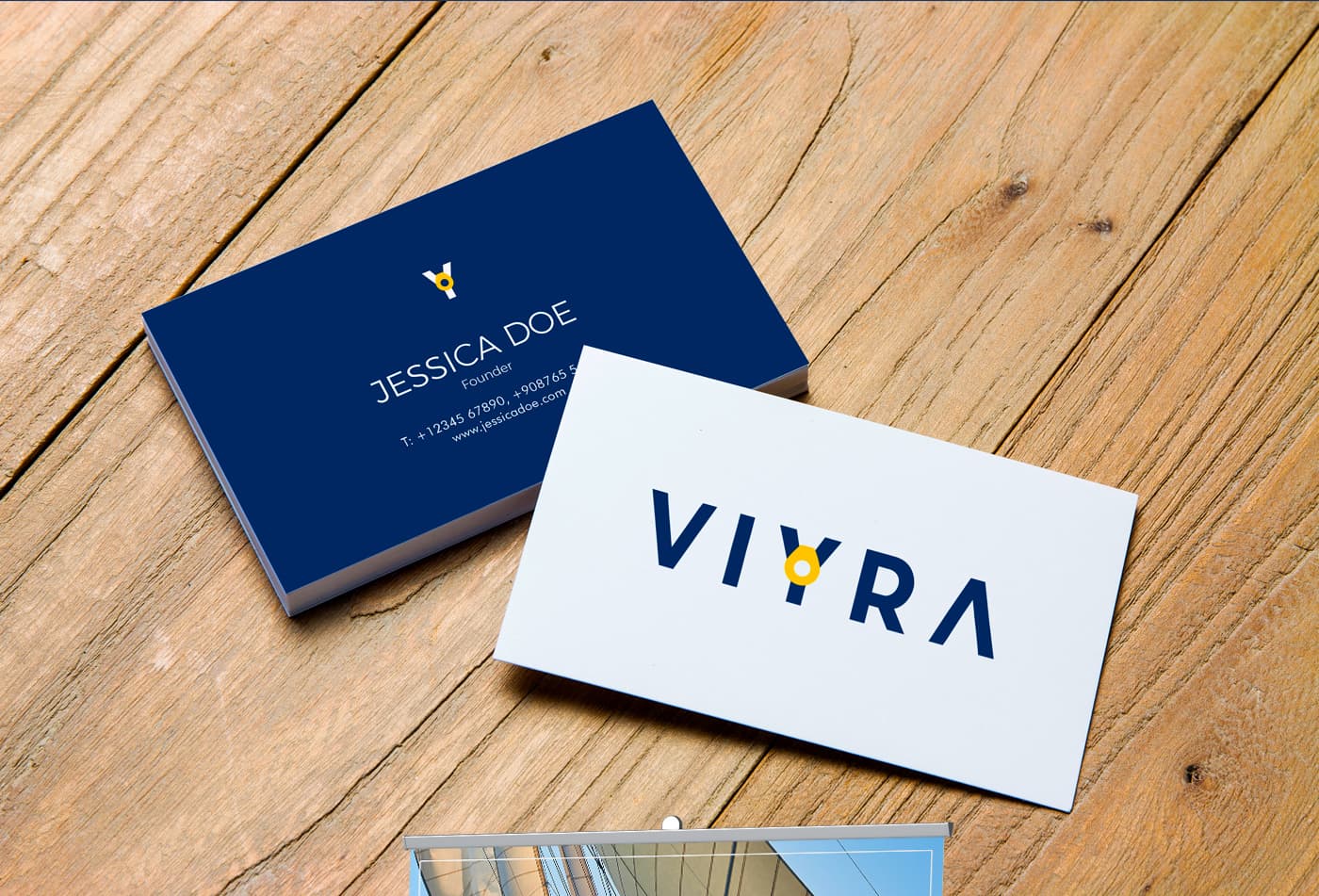 Tarjetas de visita azul marino y blanca con el logotipo Viyra sobre una mesa de madera