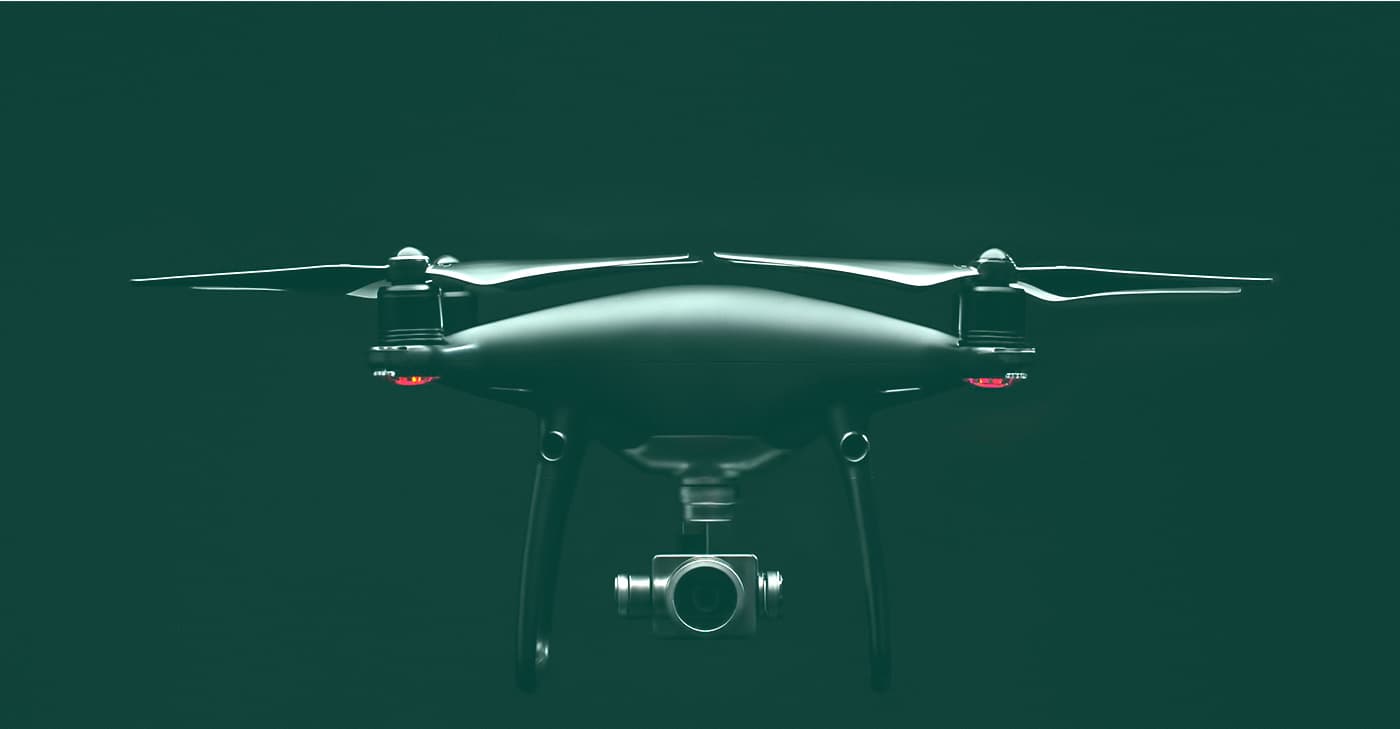 Photo of a camera drone suspended against a dark green background