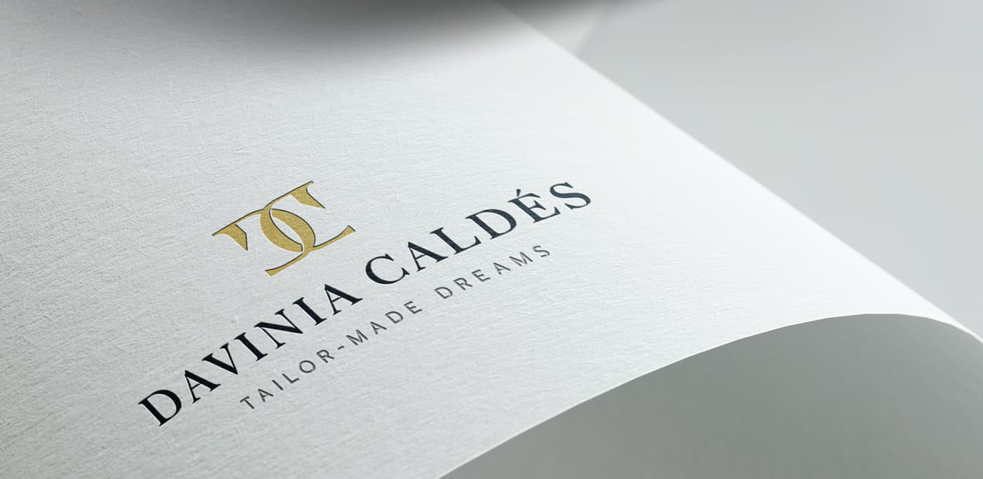 Logotip gravat en relleu daurat sobre paper texturitzat blanc