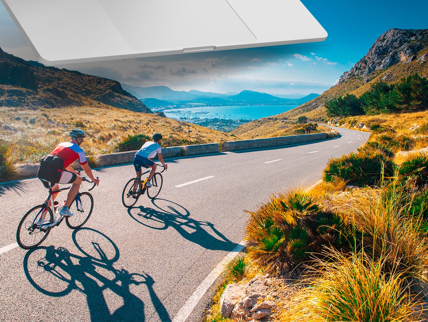 Fotomuntatge de dos ciclistes en carretera de muntanya al costat de la badia