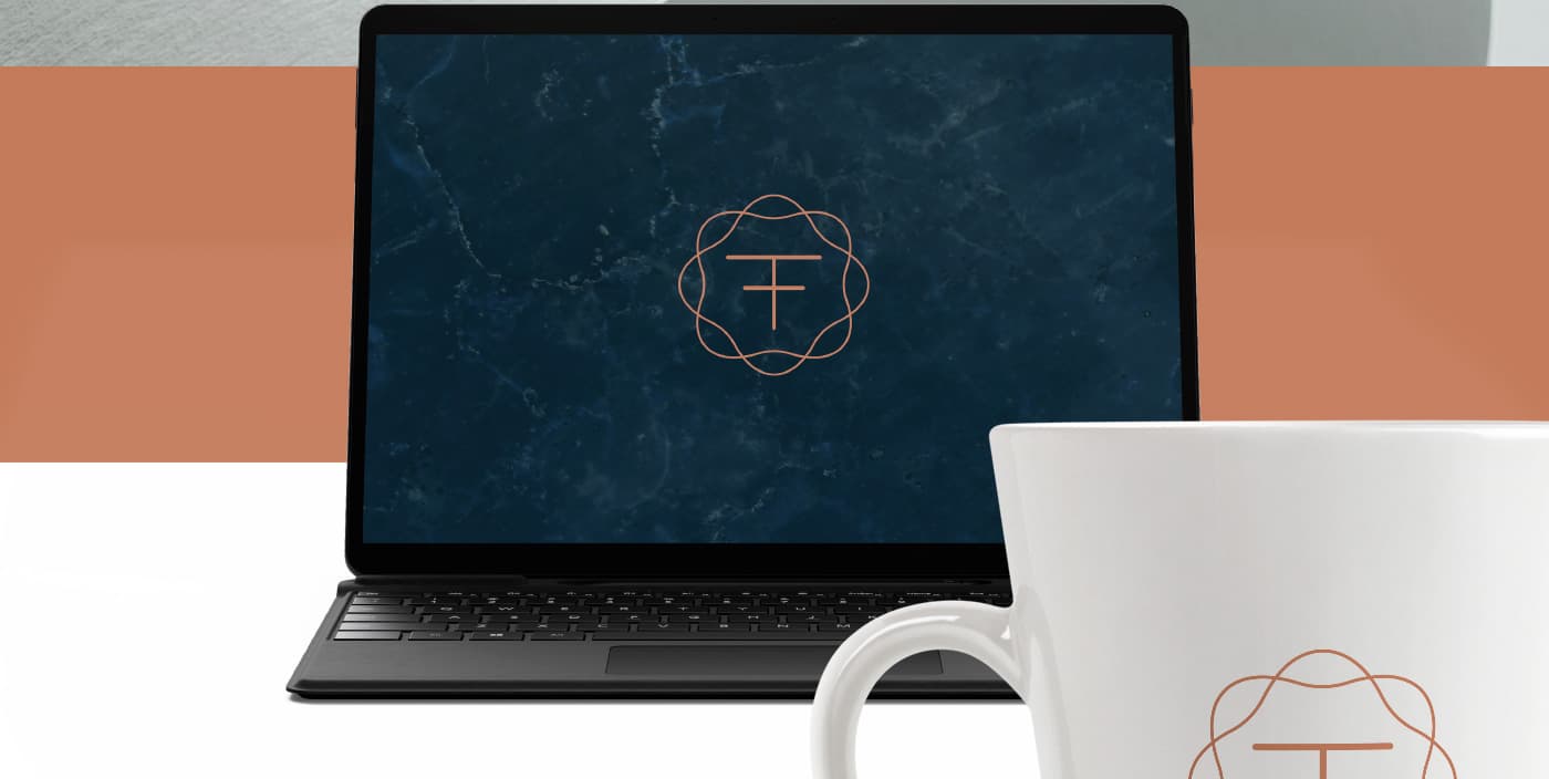 Ordenador portátil y taza blanca con el símbolo del logotipo sobre fondo de mármol azul