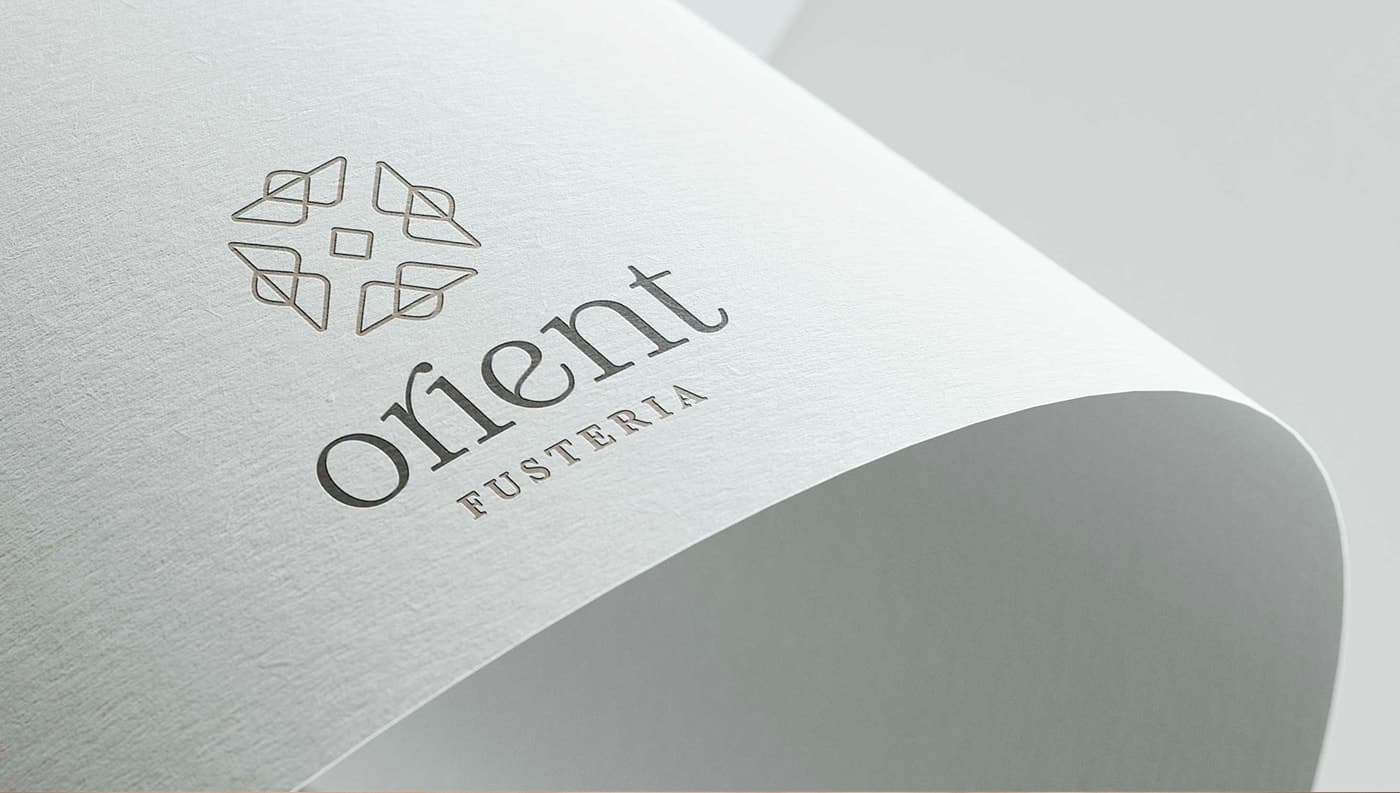 Logotip de Fusteria Orient gravat en relleu sobre paper texturitzat blanc