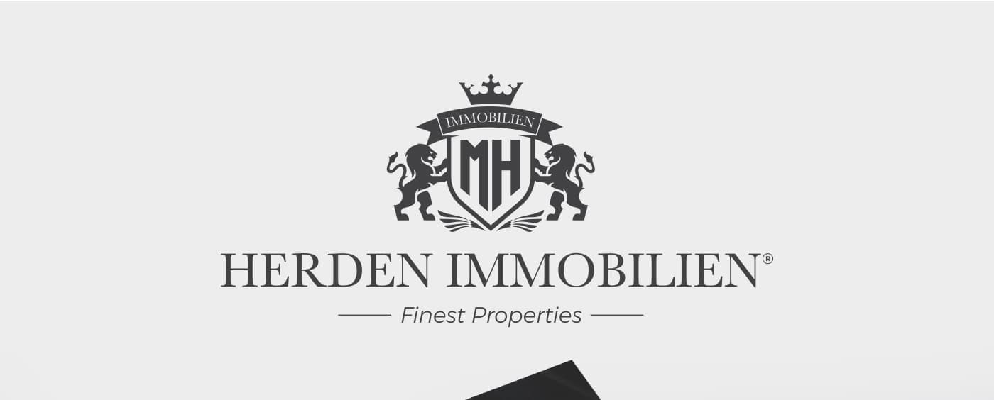 Logotip de Herden Immobilien amb escut, corona i lleons heràldics en gris fosc