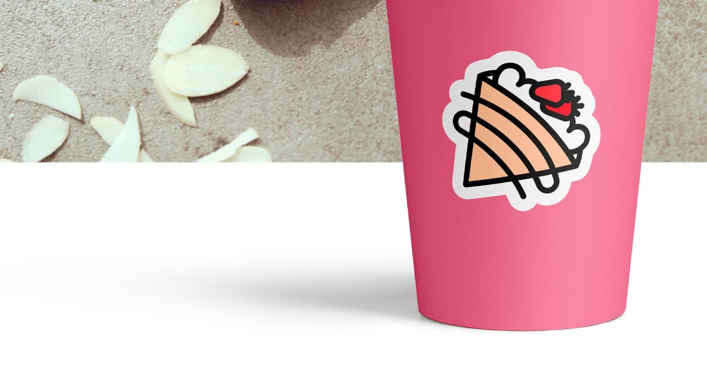 Vaso rosa con el icono del crep junto a almendras laminadas sobre la mesa