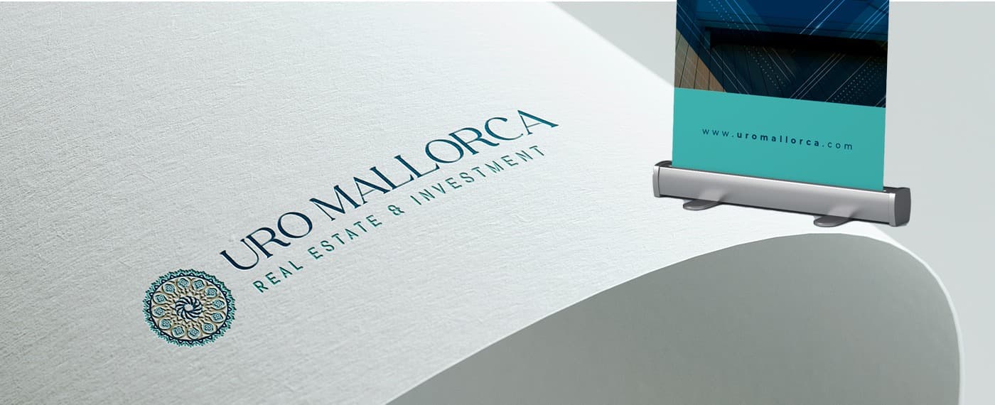 Detall del logotip amb el rosetó geomètric imprès sobre paper texturitzat al costat d'un roll-up
