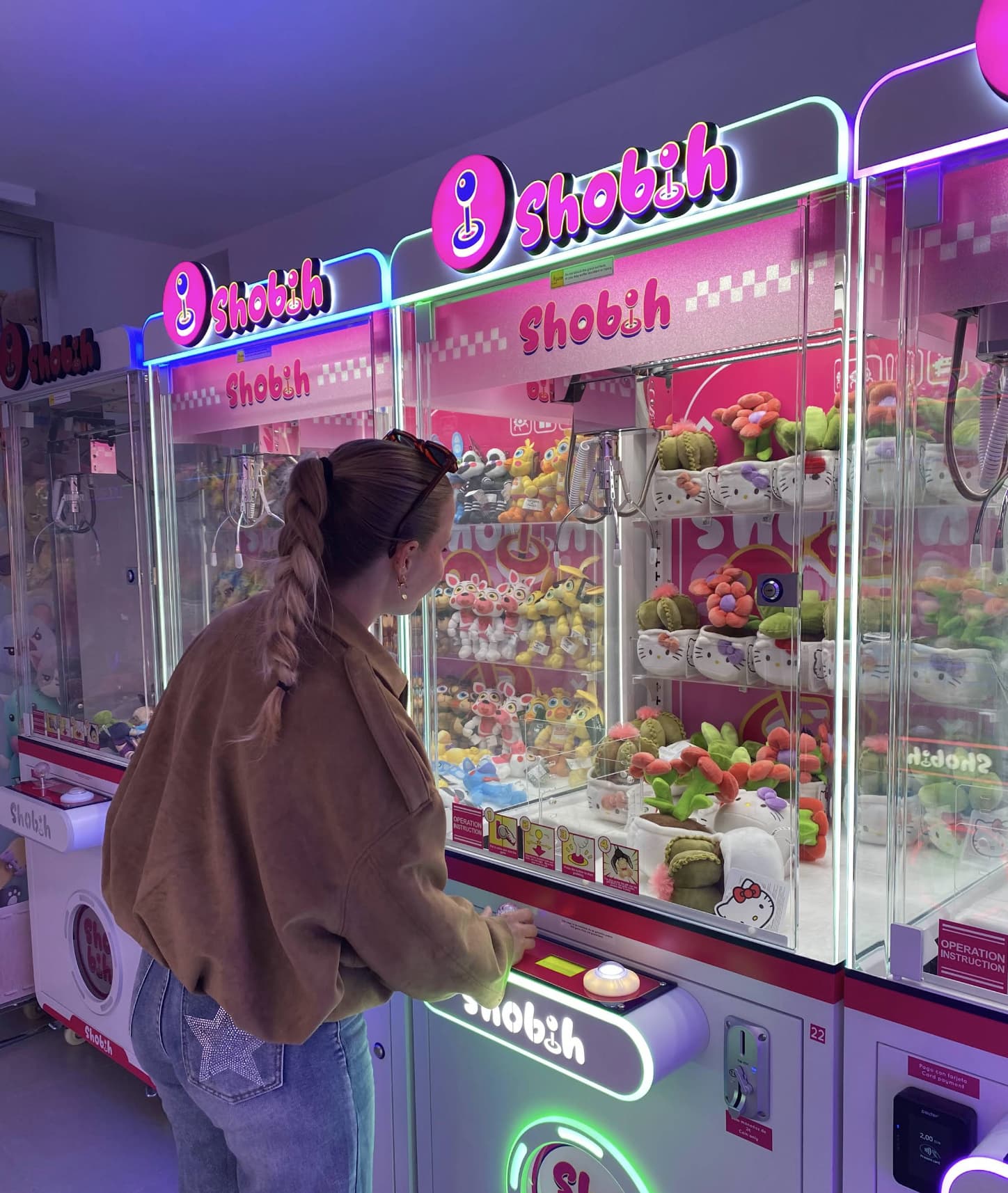 Woman playing on a pink neon-lit claw machine